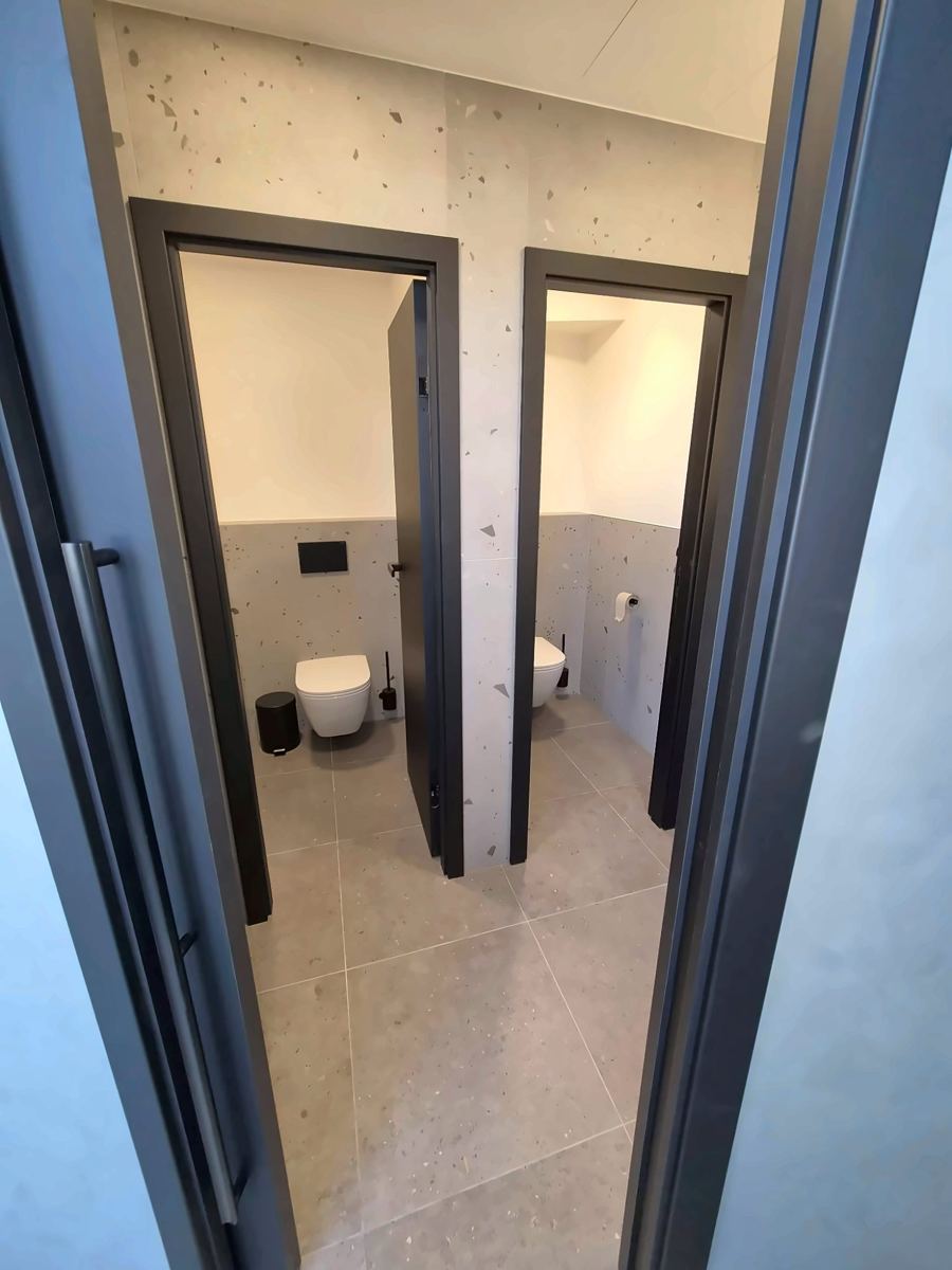 WC obložené velkoformátovým obkladem s terazzo vzorem a podomítkovým tlačítkem